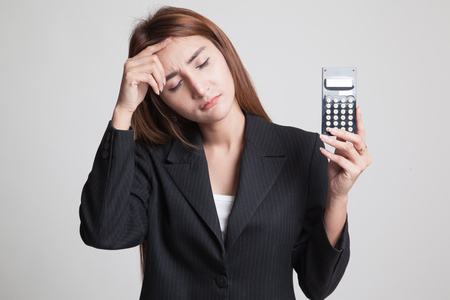 Asian woman got  headache with calculator on gray backgroundの写真素材