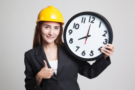 Asian engineer woman thumbs up with a clock on gray backgroundの写真素材