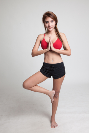 Beautiful Asian healthy girl do yoga pose on gray backgroundの写真素材