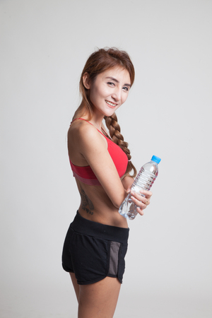 Beautiful Asian healthy girl with bottle of drinking water on gray backgroundの写真素材