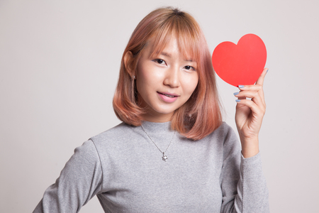 Asian woman with red heart on gray backgroundの写真素材