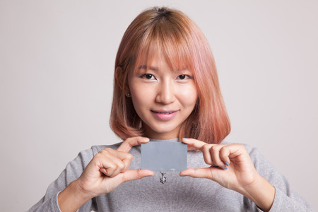 Young Asian woman smile with blank card on gray backgroundの写真素材