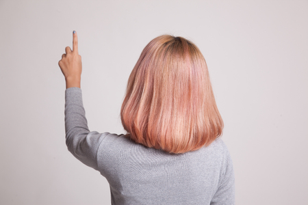 Back of Asian woman touching the screen with her finger on gray backgroundの写真素材