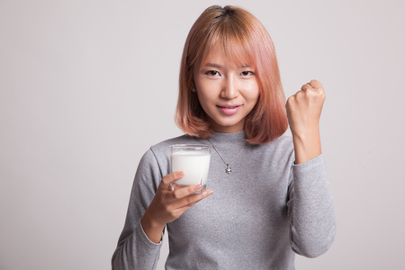 Healthy Asian woman drinking a glass of milk on gray backgroundの写真素材
