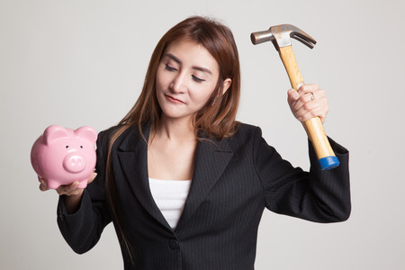Asian woman with pig coin bank and hammer on gray backgroundの写真素材