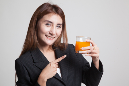 Young Asian woman point to orange juice on gray backgroundの写真素材