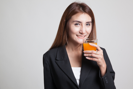 Young Asian woman drink orange juice on gray backgroundの写真素材