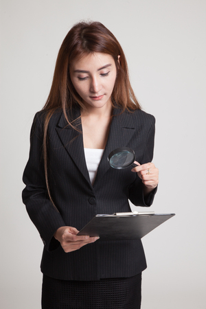 Young Asian woman with a magnifying glass check report on gray backgroundの写真素材