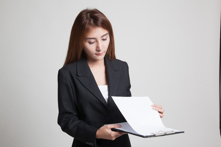 Young Asian business woman read paper on clipboard on gray backgroundの写真素材