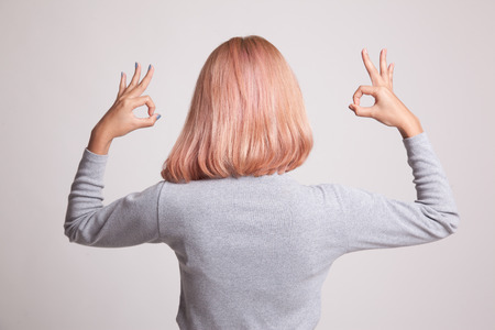 Back view of Asian woman show double OK hand sign on gray backgroundの写真素材