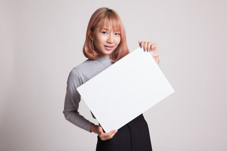 Young Asian woman with white blank sign on gray background