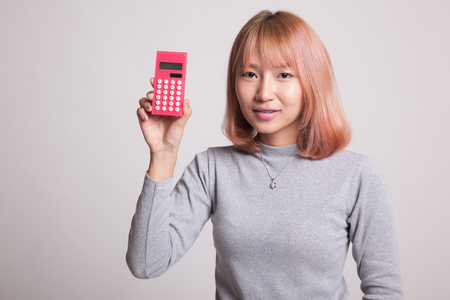 Asian woman smile with calculator on gray backgroundの写真素材