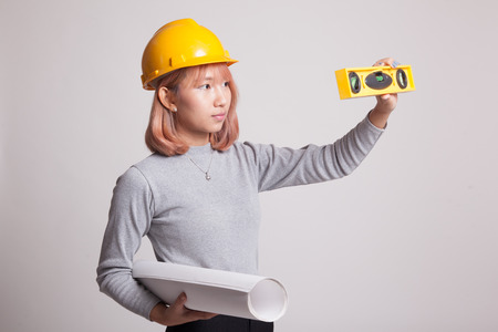 Asian engineer woman with blueprints and level on gray backgroundの写真素材