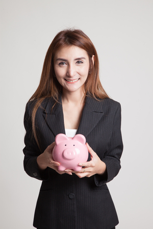 Young Asian woman with a pig coin bank on gray backgroundの写真素材