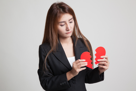 Beautiful young Asian woman with broken heart on gray backgroundの写真素材