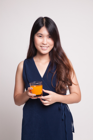 Young Asian woman drink orange juice on gray backgroundの写真素材