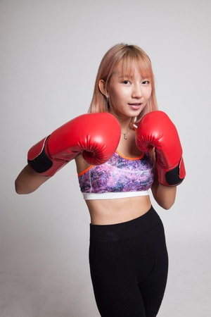 Beautiful healthy Asian girl with red boxing glove on gray backgroundの写真素材