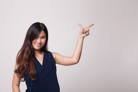 Young Asian woman smile and point on gray backgroundの写真素材
