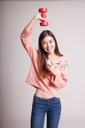Healthy Asian woman drinking a glass of milk and dumbbell on gray backgroundの写真素材