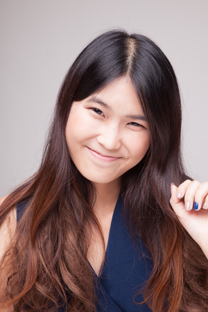 Portrait of beautiful young Asian woman on gray backgroundの写真素材
