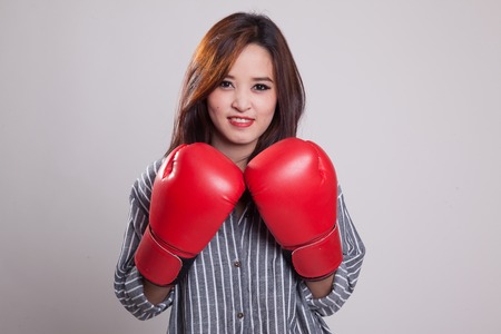 Young Asian woman with red boxing gloves on gray backgroundの写真素材