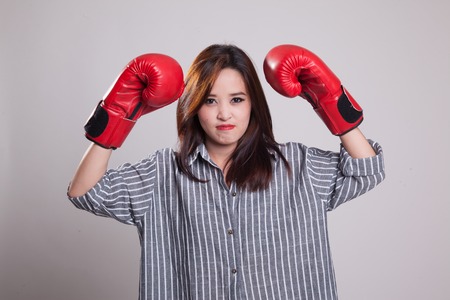 Young Asian woman with red boxing gloves on gray backgroundの写真素材