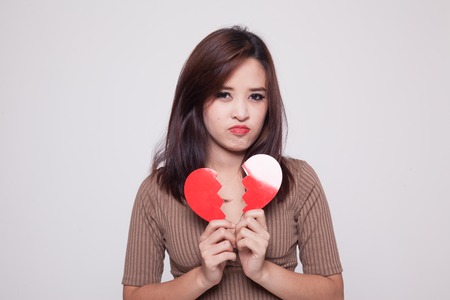Beautiful young Asian woman with broken heart on gray backgroundの写真素材