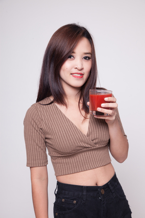Young Asian woman drink tomato juice on gray backgroundの写真素材