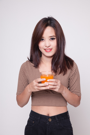 Young Asian woman drink orange juice on gray backgroundの写真素材