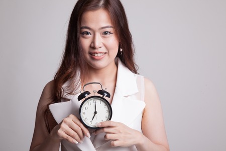 Young Asian woman smile with a clock on gray backgroundの写真素材