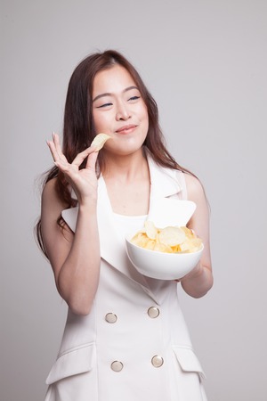 Young Asian woman eat potato chips on gray backgroundの写真素材