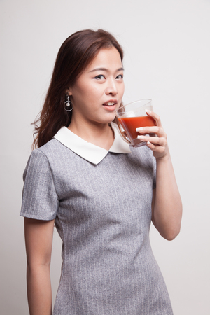 Young Asian woman drink tomato juice on gray backgroundの写真素材