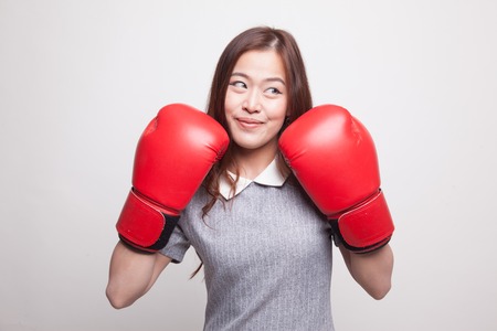 Young Asian woman with red boxing gloves on gray backgroundの写真素材