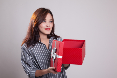 Young Asian woman open a gift box on gray backgroundの写真素材