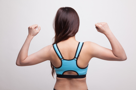 Back of Asian  healthy  girl in sport dresses  flex bicep on white backgroundの写真素材