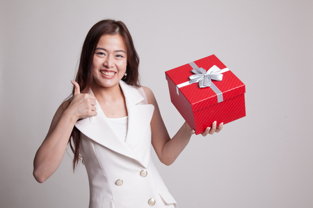 Asian woman thumbs up with a gift box on gray backgroundの写真素材