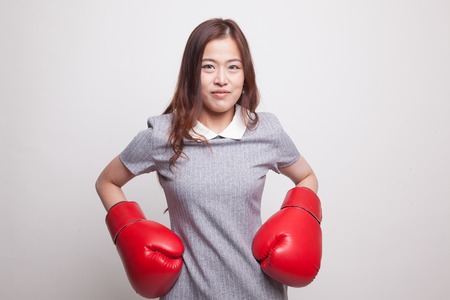 Young Asian woman with red boxing gloves on gray backgroundの写真素材