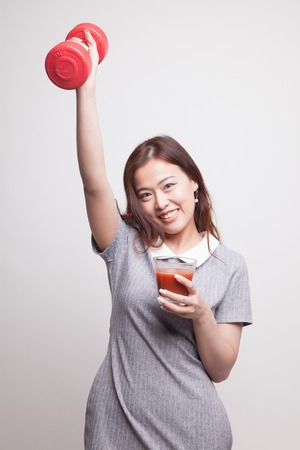 Young healthy Asian woman with dumbbell and  tomato juice on gray backgroundの写真素材