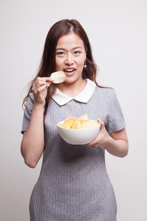 Young Asian woman eat potato chips on gray backgroundの写真素材