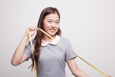 Young Asian woman with measuring tape on gray backgroundの写真素材