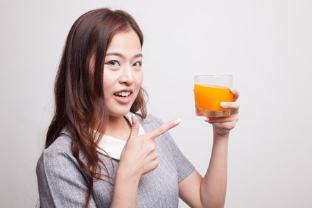 Young Asian woman point to orange juice on gray backgroundの写真素材