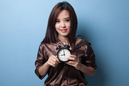 Young Asian woman smile with a clock on blue backgroundの写真素材