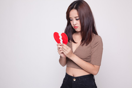 Beautiful young Asian woman with broken heart on gray backgroundの写真素材
