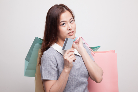 Young Asian woman with shopping bag and blank card on gray backgroundの写真素材