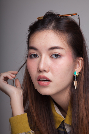 Portrait of beautiful young Asian woman with  yellow sunglasses on gray backgroundの写真素材
