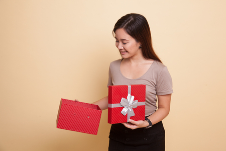 Young Asian woman open a gift box on beige backgroundの写真素材