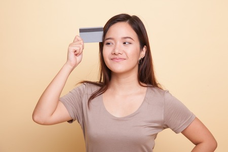 Young Asian woman think with a blank card on beige backgroundの写真素材