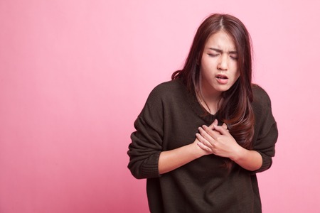 Young Asian woman got chest pain on pink background