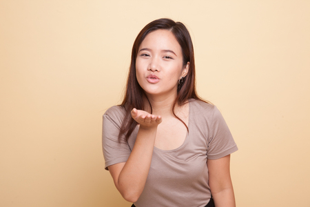 Beautiful young Asian woman blow a kiss on beige backgroundの写真素材