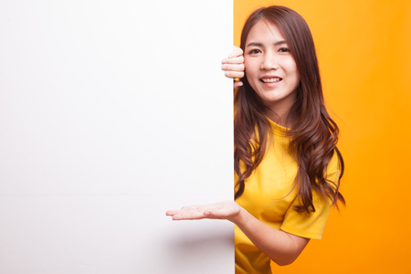 Young Asian woman present blank sign with palm hand in yellow dress on yellow backgroundの写真素材